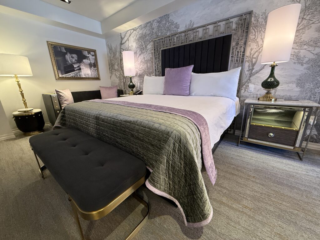 A close up of the hotel bed against an accent wall with a bench at the foot. 