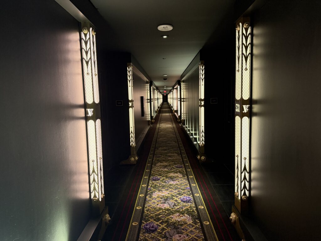 A hotel hallway, with light bars extending into the distance on both sides of the hall. 