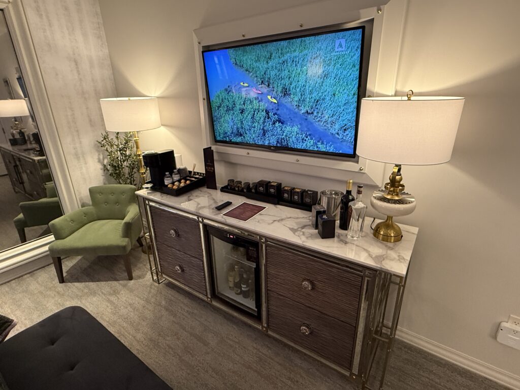 A wall mounted TV hanging above the minibar. 