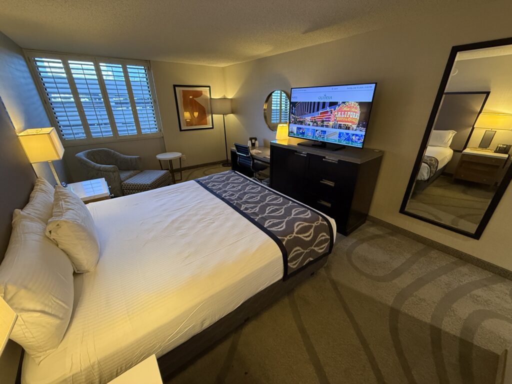 An angle of the room, which shows the king bed pointed at a TV and a full length mirror. 