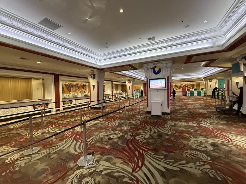 A large hotel lobby, with a front desk, automated kiosks, and clown decor on the pillars.