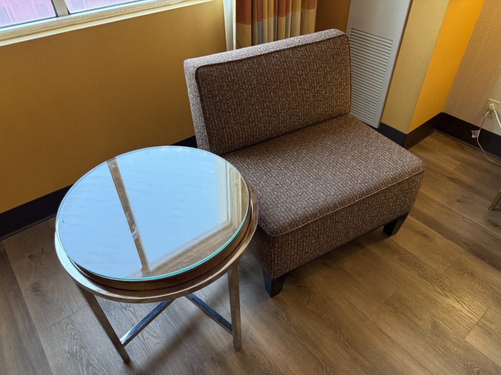 A small brown chair next to a glass end table.