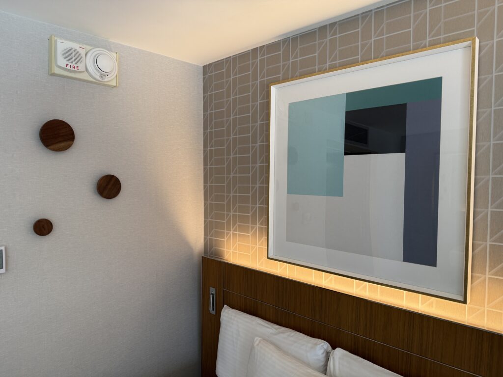 A corner of the room which shows the illuminated headboard and wall art.