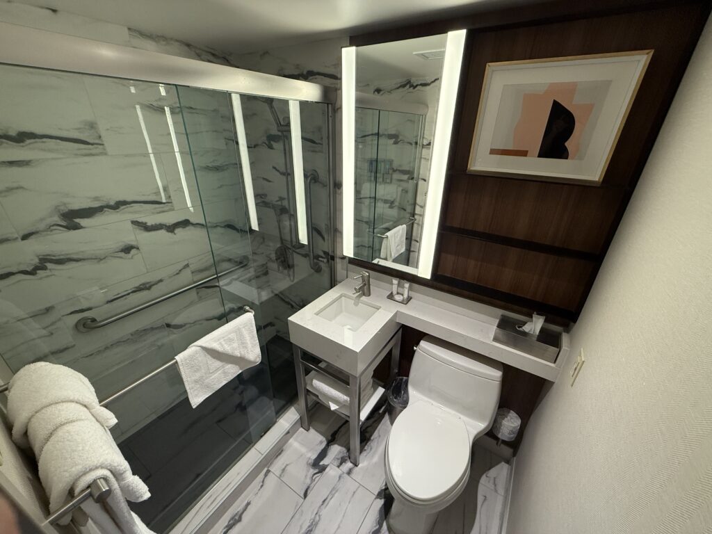 A very compact bathroom with a toilet, tiny sink, and shower. 