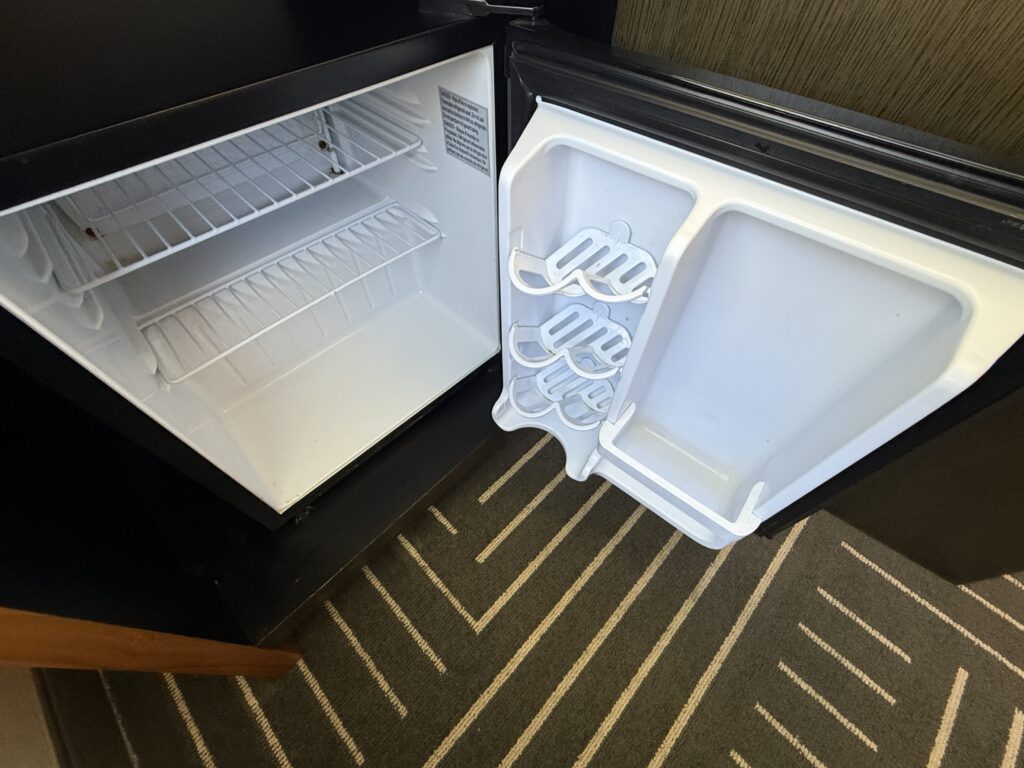 An empty mini fridge, open to show it's emptiness. 