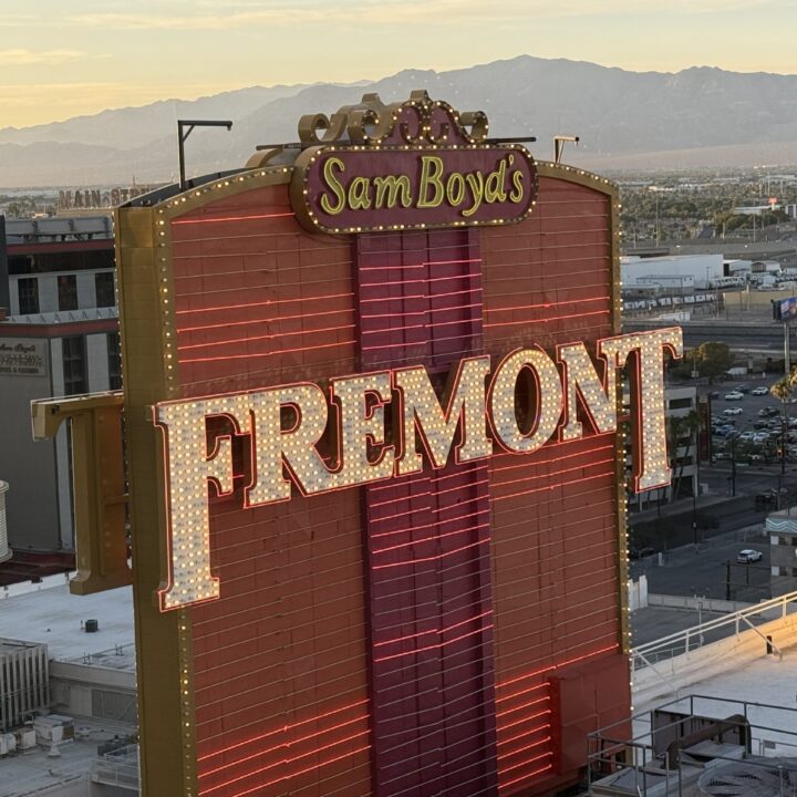 Sam Boyd's neon sign with Fremont letters, set against a desert cityscape and distant mountains at dusk.