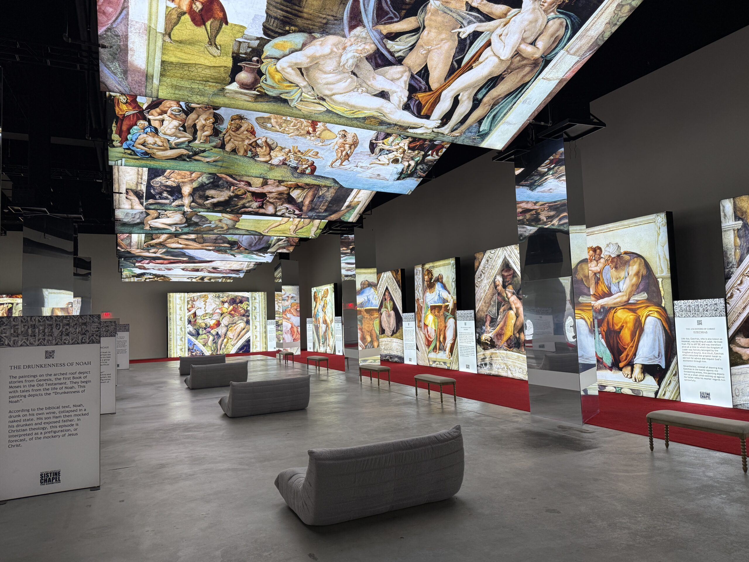 Illuminated painings hang on the ceiling above couches. Paintings are also on the wall in the background.