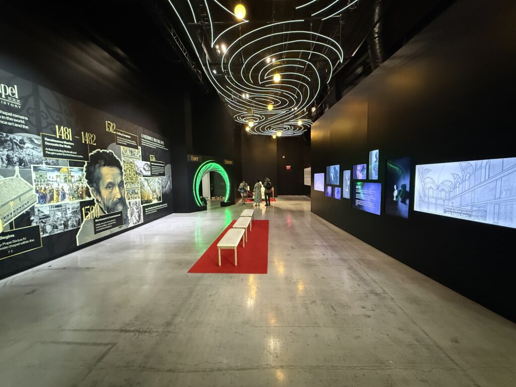 Entryway to Michelangelo's Sistine Chapel, which has a timeline of his life on the left and video content playing on the right. 