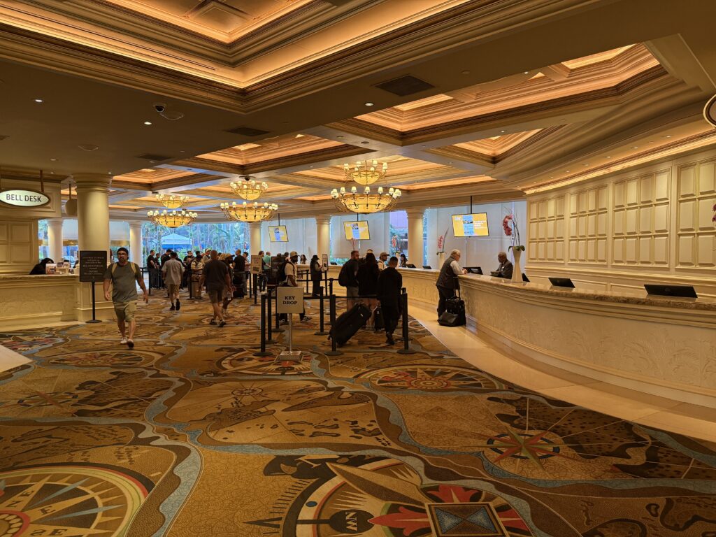 TI's hotel front desk, with illuminated crown moulding along the ceiling and decorative chandeliers.