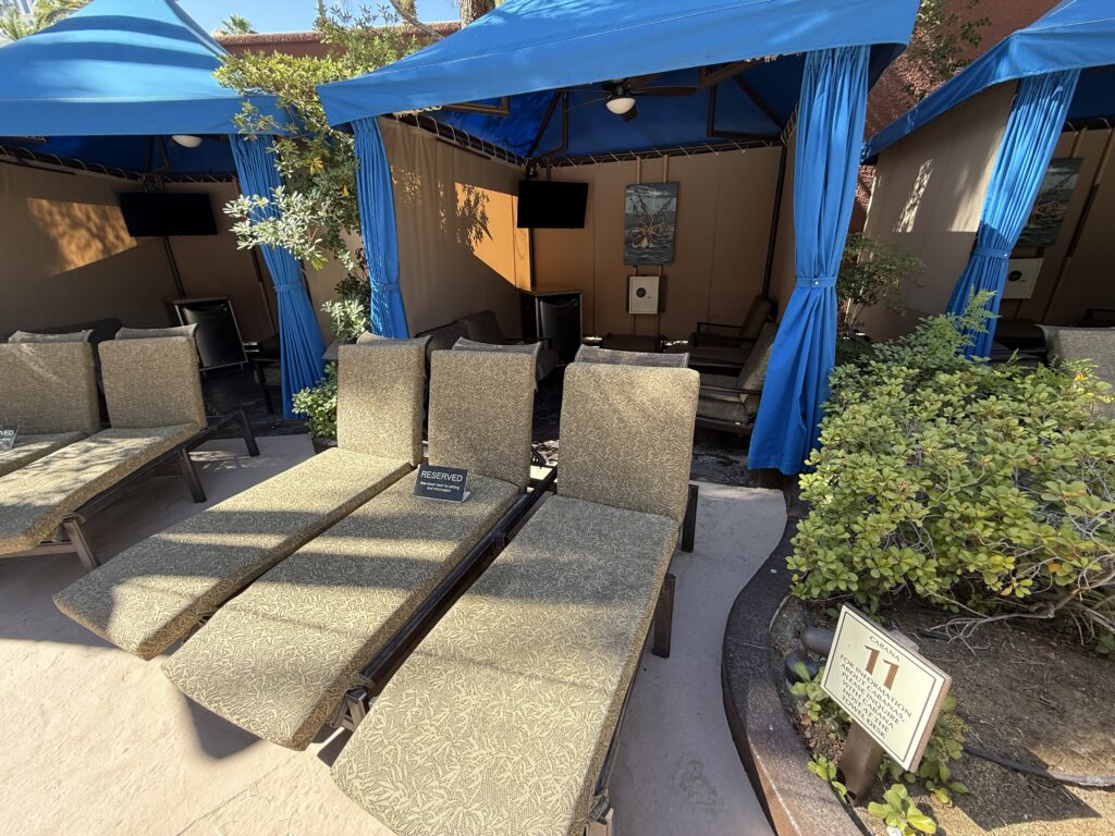 One of TI's cabanas, which has a TV mounted and 3 loungers in front.