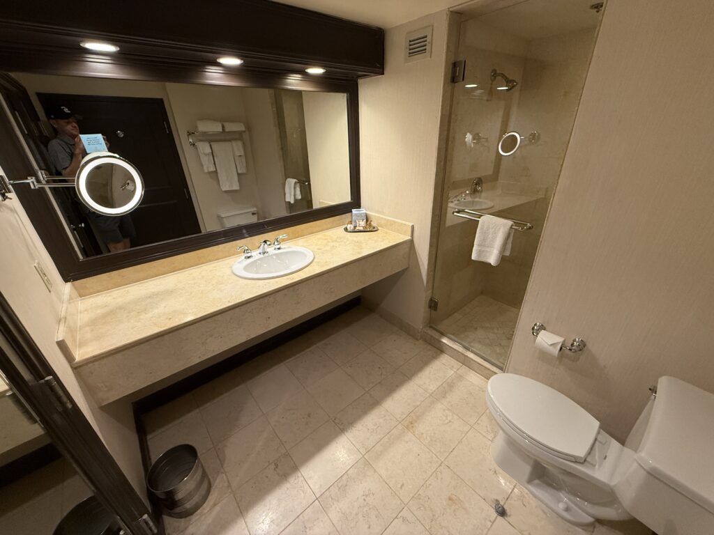 A single sink vanity, toilet, and glass door leading into a shower.