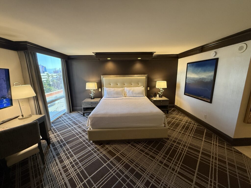 Head on shot of the king bed with a window to the left and wall art to the right.