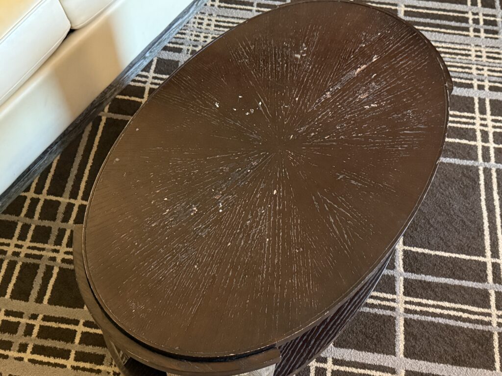 Round dark brown coffee table with worn, scratched surface.