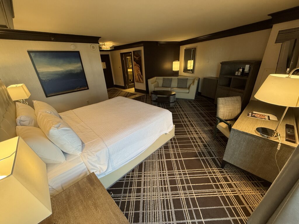 Another wide angle view of the room that shows the bed in the foreground and the 2 seat couch in the background.