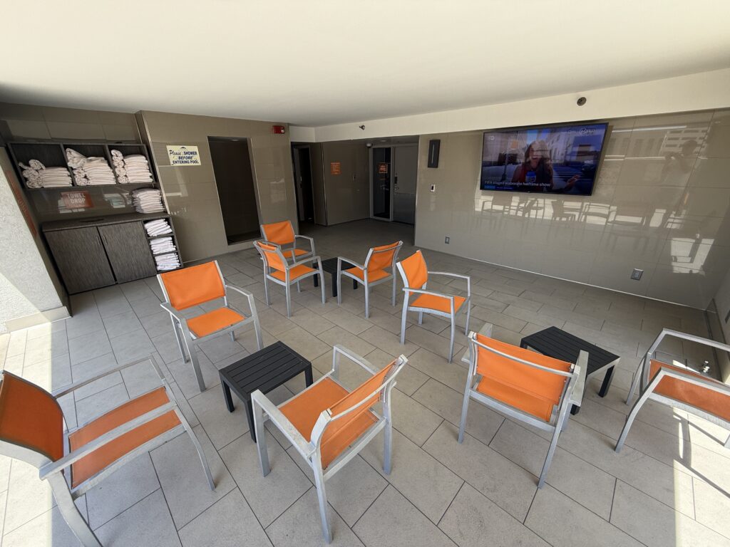 A covered area near the pool with a TV and seating. 