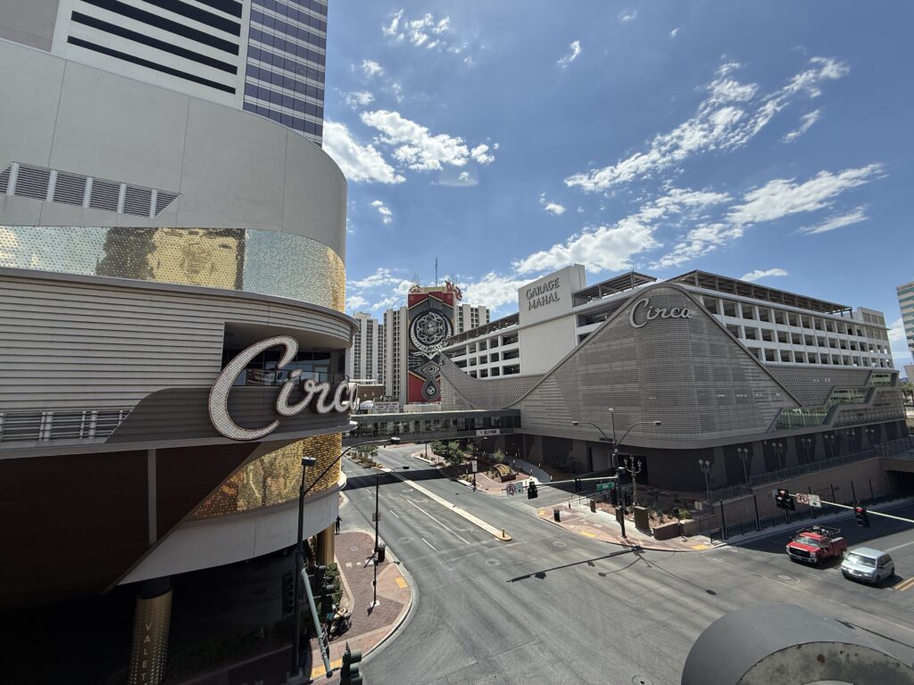 Wide-angle view of the Circa hotel and casino with curved metallic facade and prominent sign under a bright blue sky