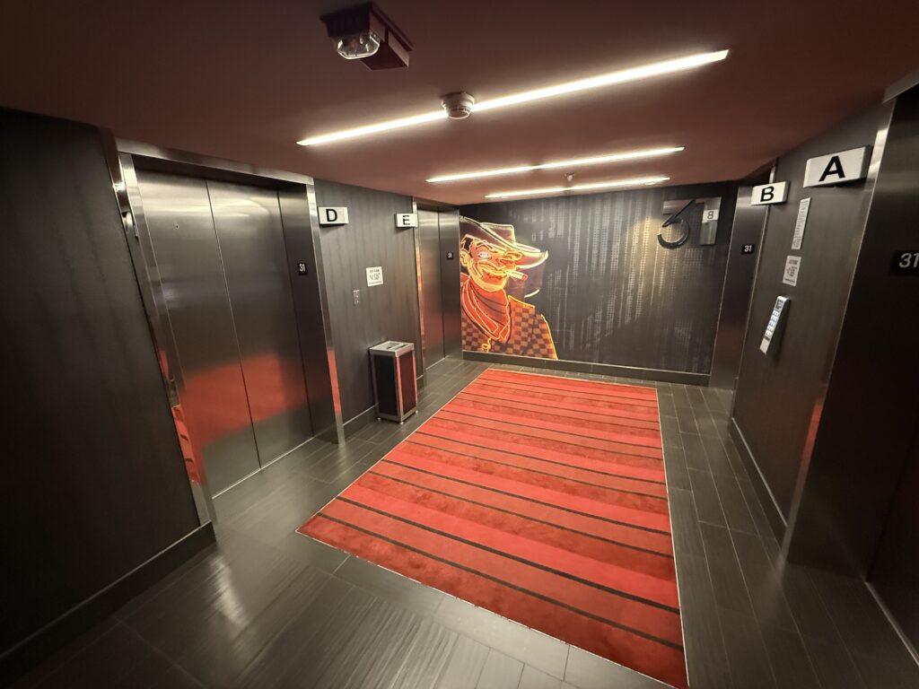 Elevator lobby with black walls, red carpeting, and a mural of Vegas Vic on the back wall.
