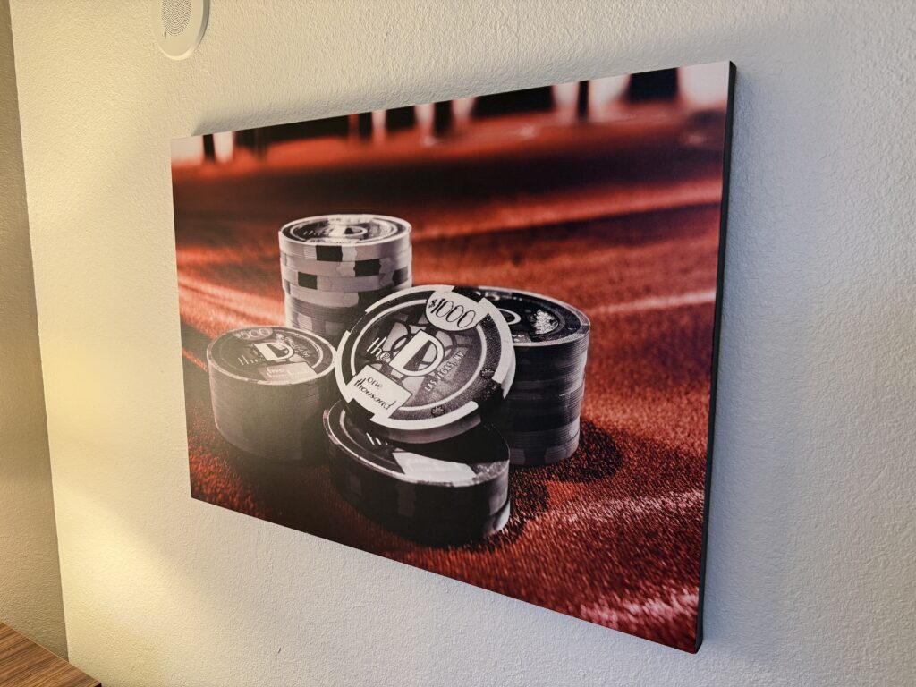 Wall art depicting a stack of D casino chips on red felt.