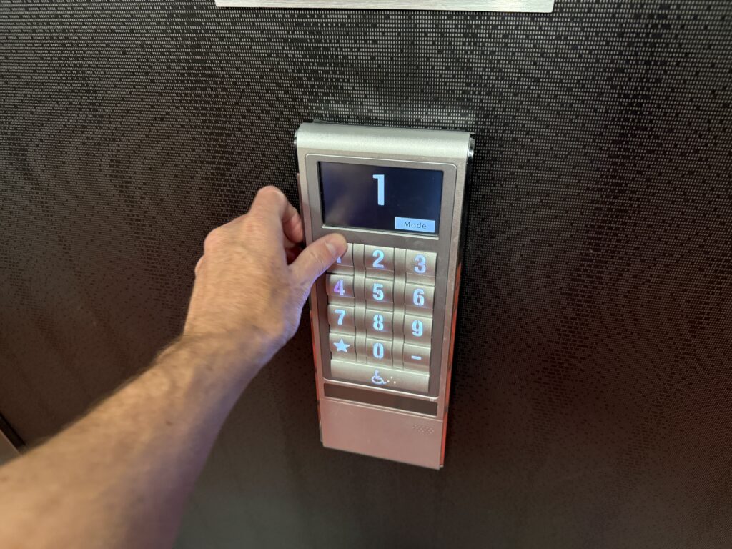 A person's hand pressing the button for the floor they are traveling to.