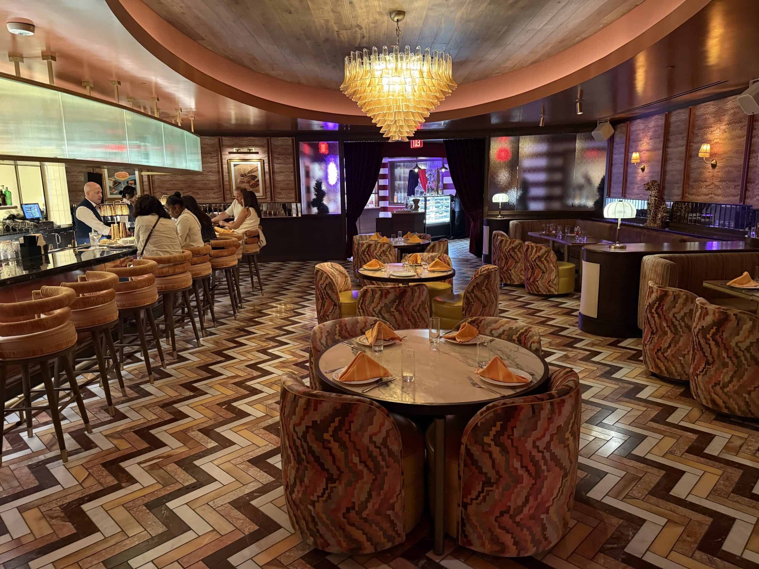 Caramella's dining area, with tables in the foreground, a bar to the left, and the entrance to the speakeasy in the background.