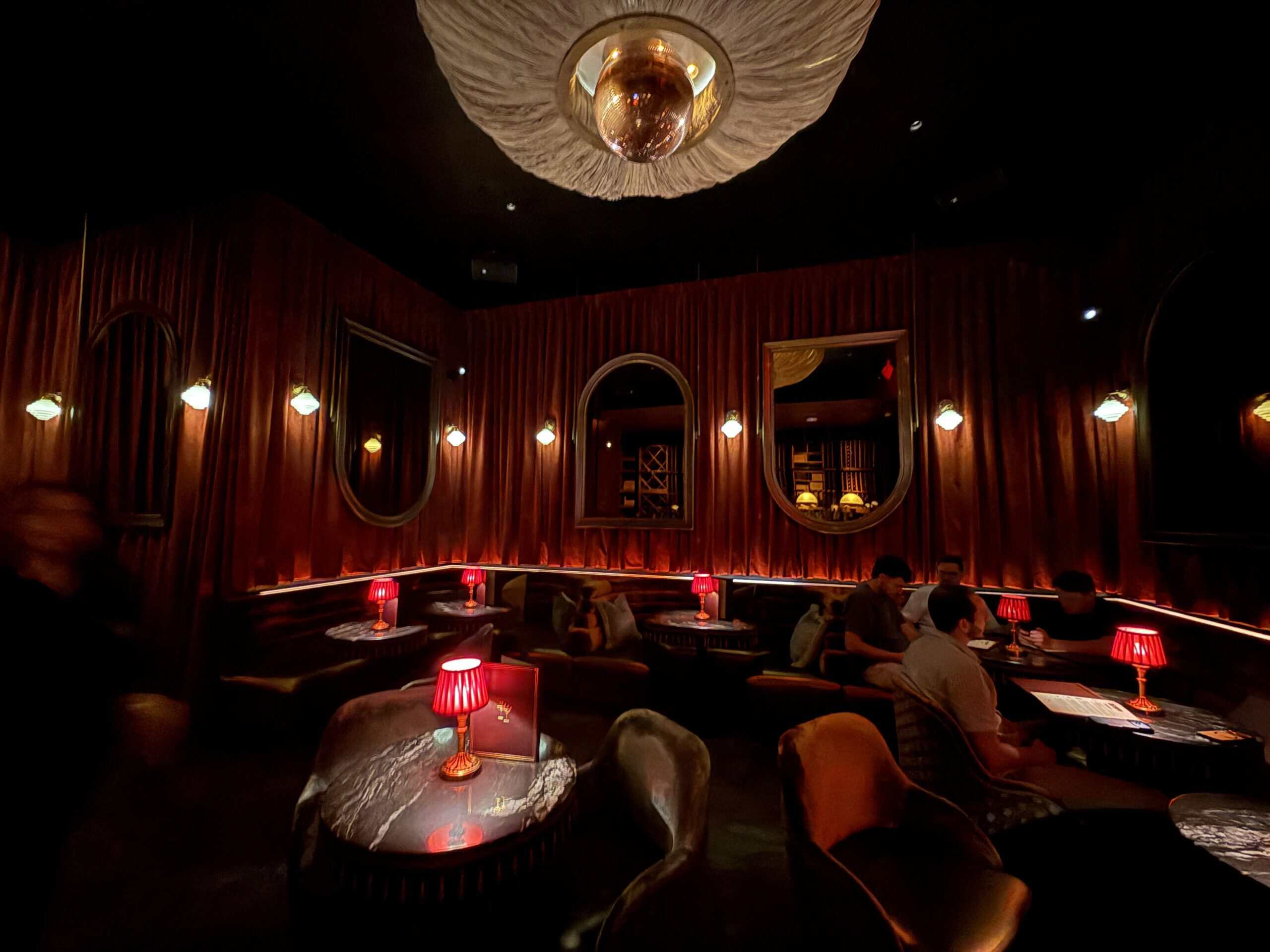 The small lounge, which has red decor, mirrors on the walls, and red lamps on the tables.