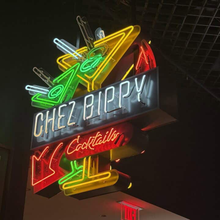 A neon sign hanging above Luchini depicting cocktail glasses that says "Chez Bippy Cocktails".