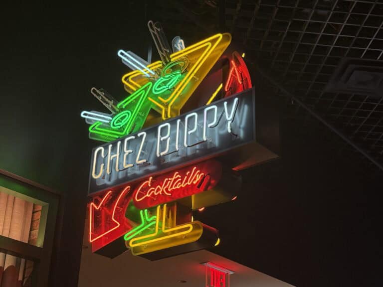 A neon sign hanging above Luchini depicting cocktail glasses that says "Chez Bippy Cocktails".