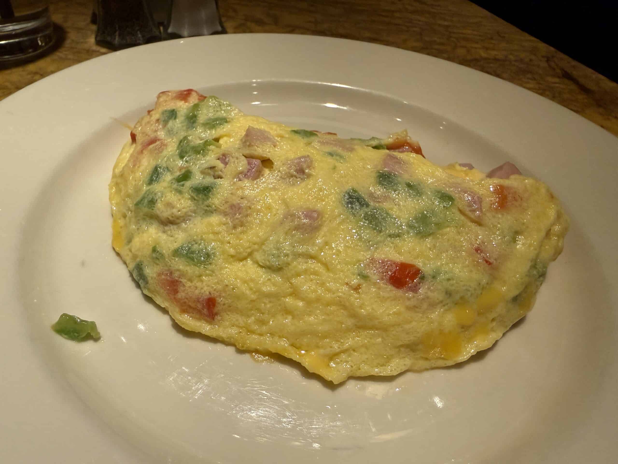 An omelette with tomatoes, green onions, and ham.