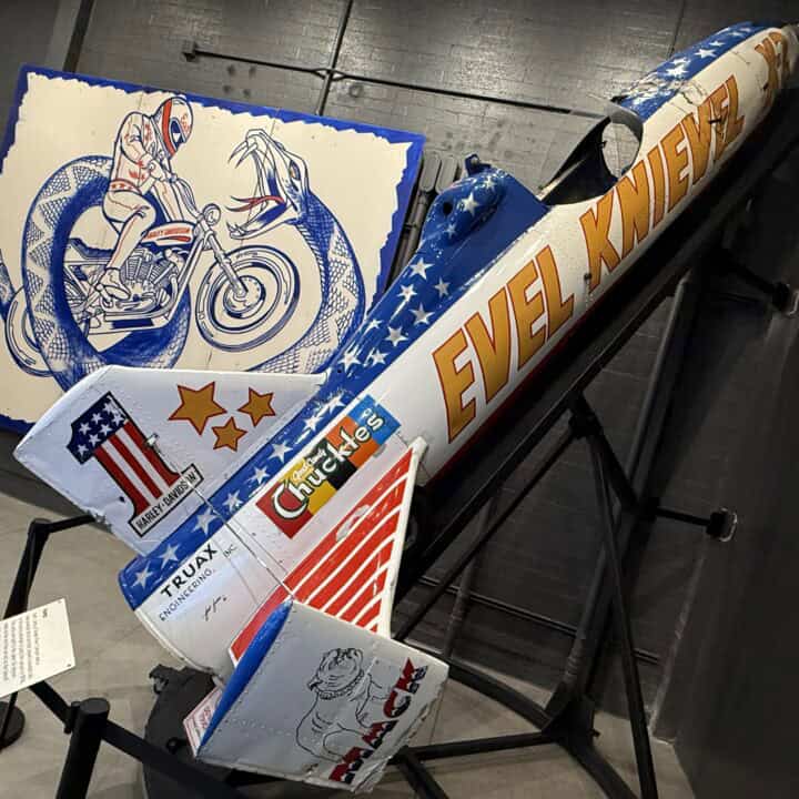 Evel Knievel's Skycycle on a ramp in front of a promotional poster for the Snake River Jump.