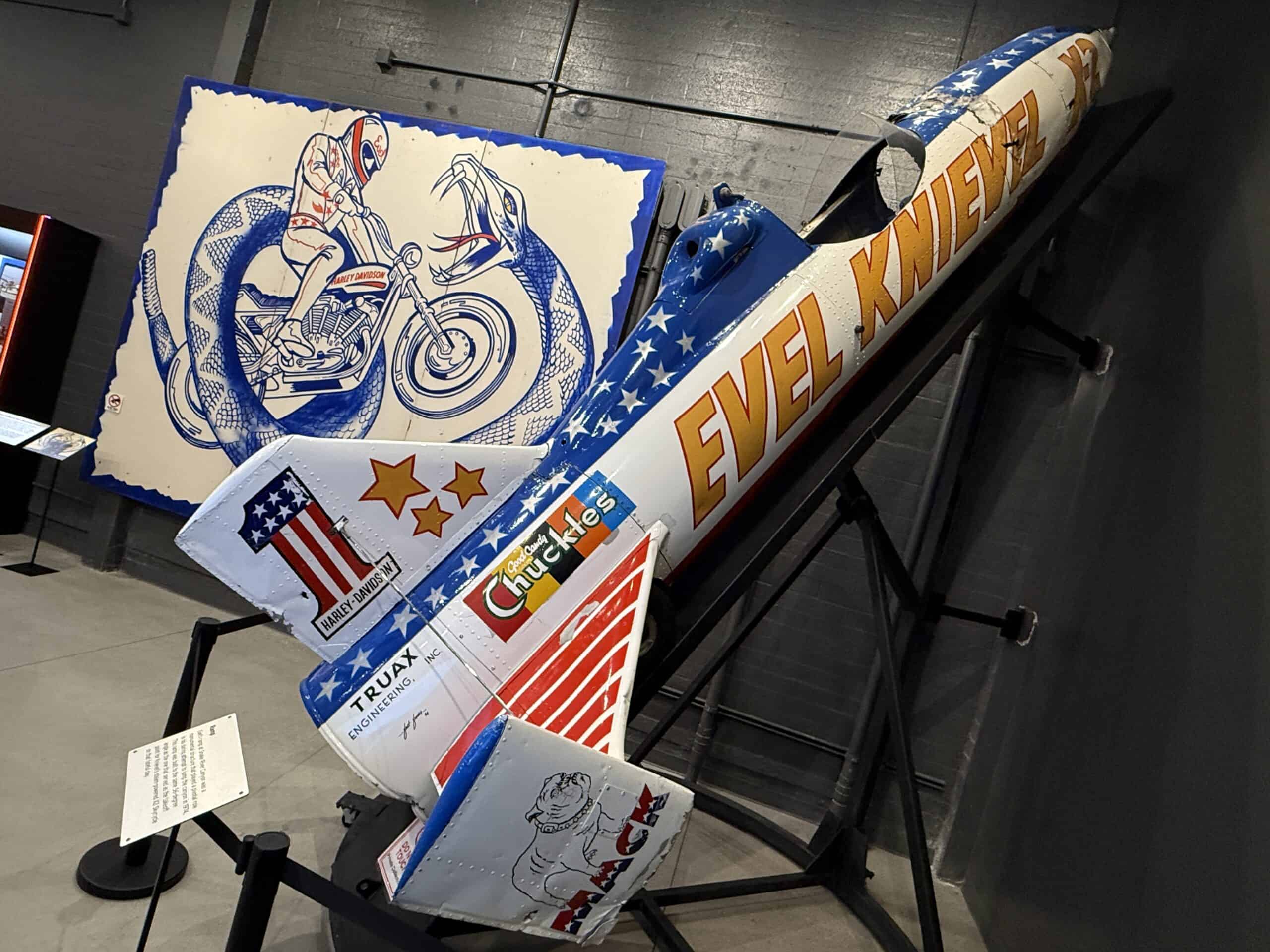 Evel Knievel's Skycycle on a ramp in front of a promotional poster for the Snake River Jump.