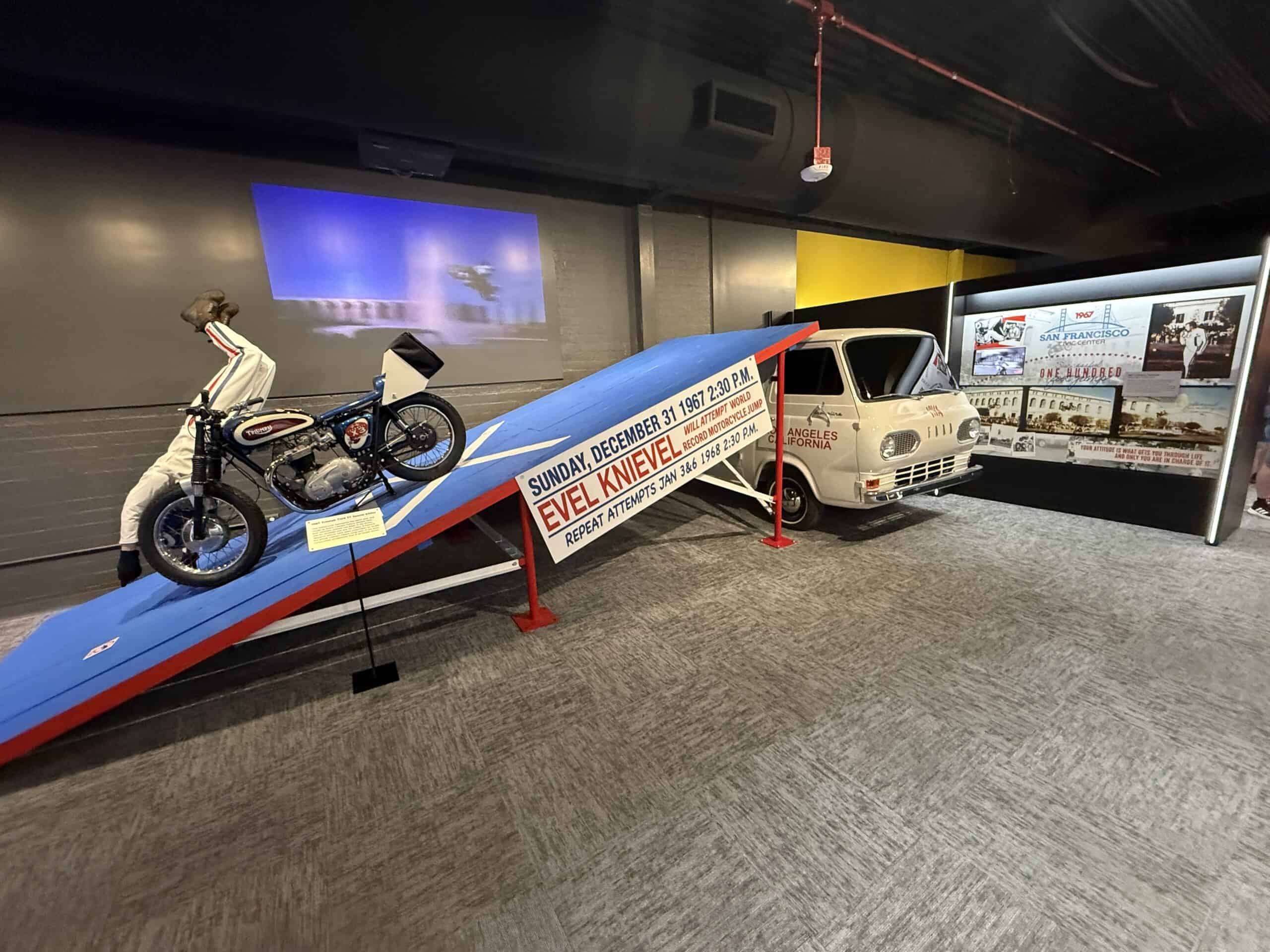 A scene depicting Evel falling off his motorcycle on the landing ramp, which is next to a bus he jumped.
