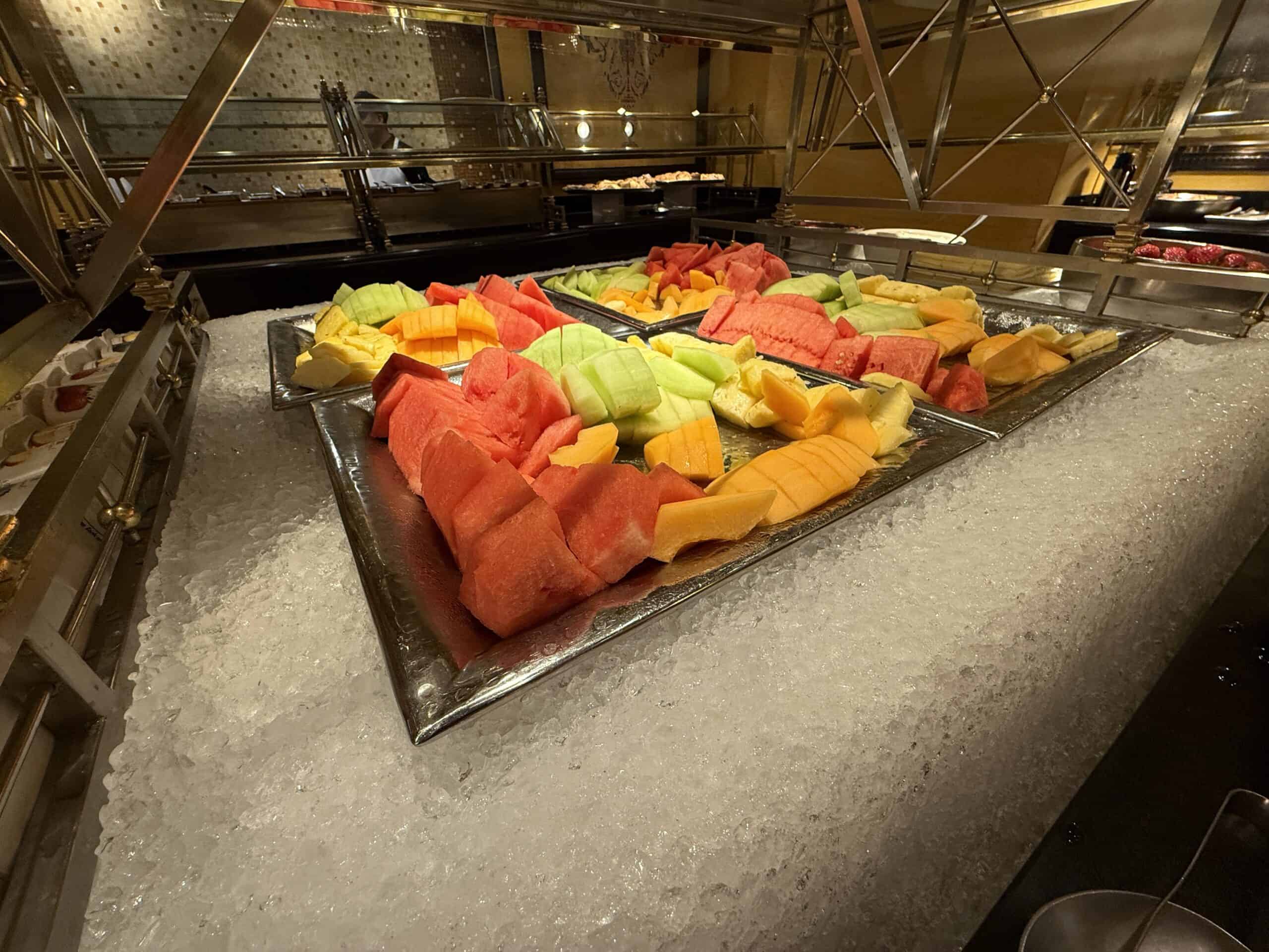 a large silver platter of fresh fruit like watermelon, honeydew, and cantelope on a bed of ice.