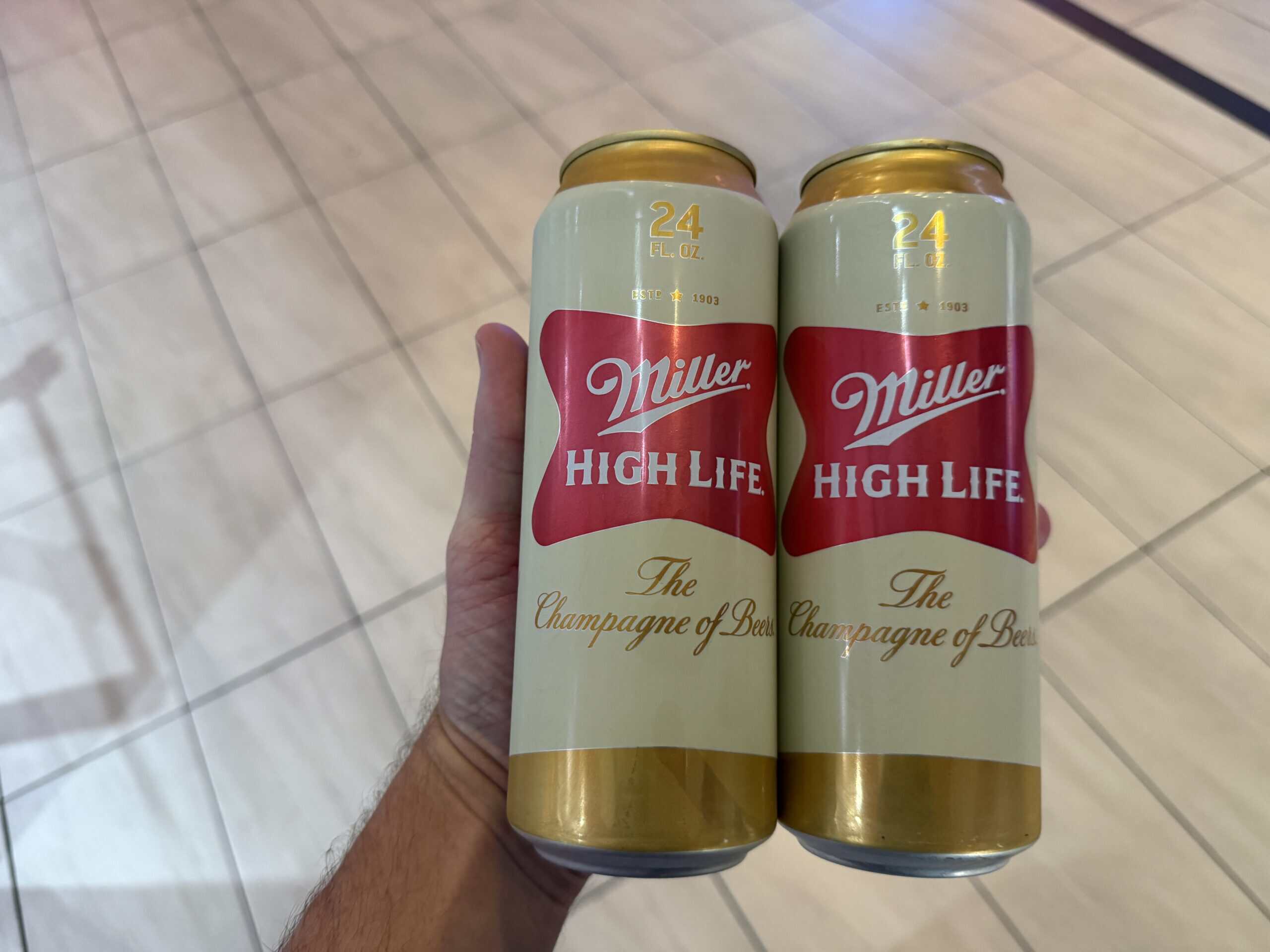 Two cans of Miller High LIfe in my hand.