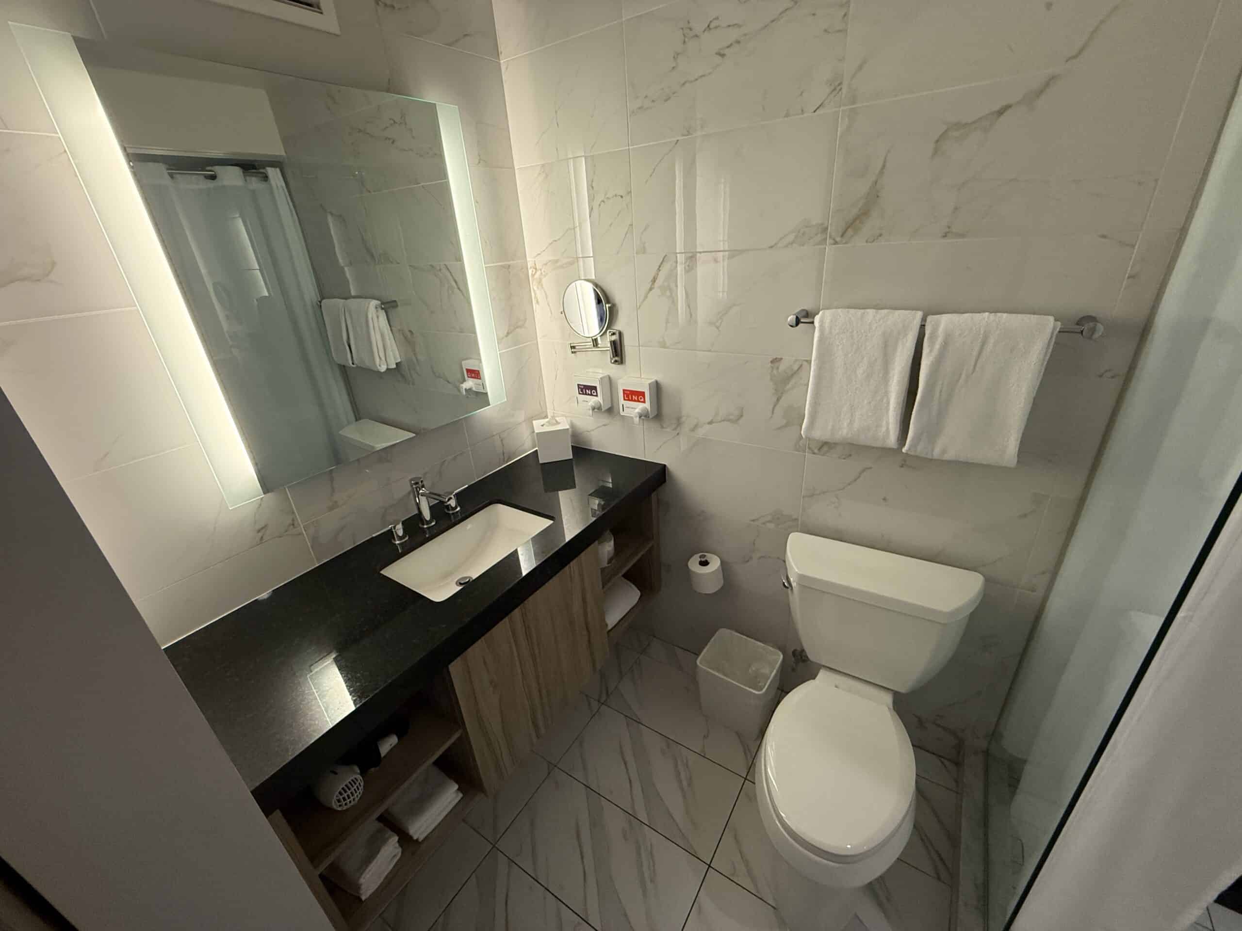 A single since vanity with a dark stone counter top to the left and toilet to it's immediate right.