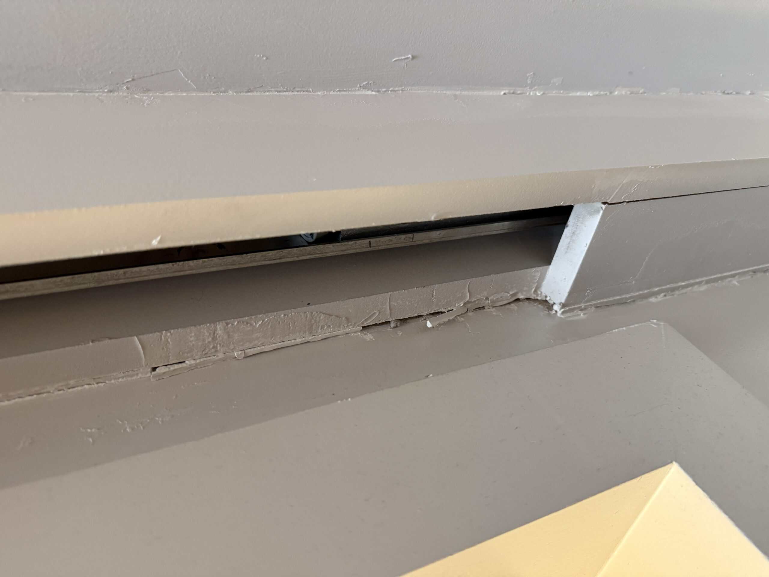 A door slide on the ceiling that has peeling paint.