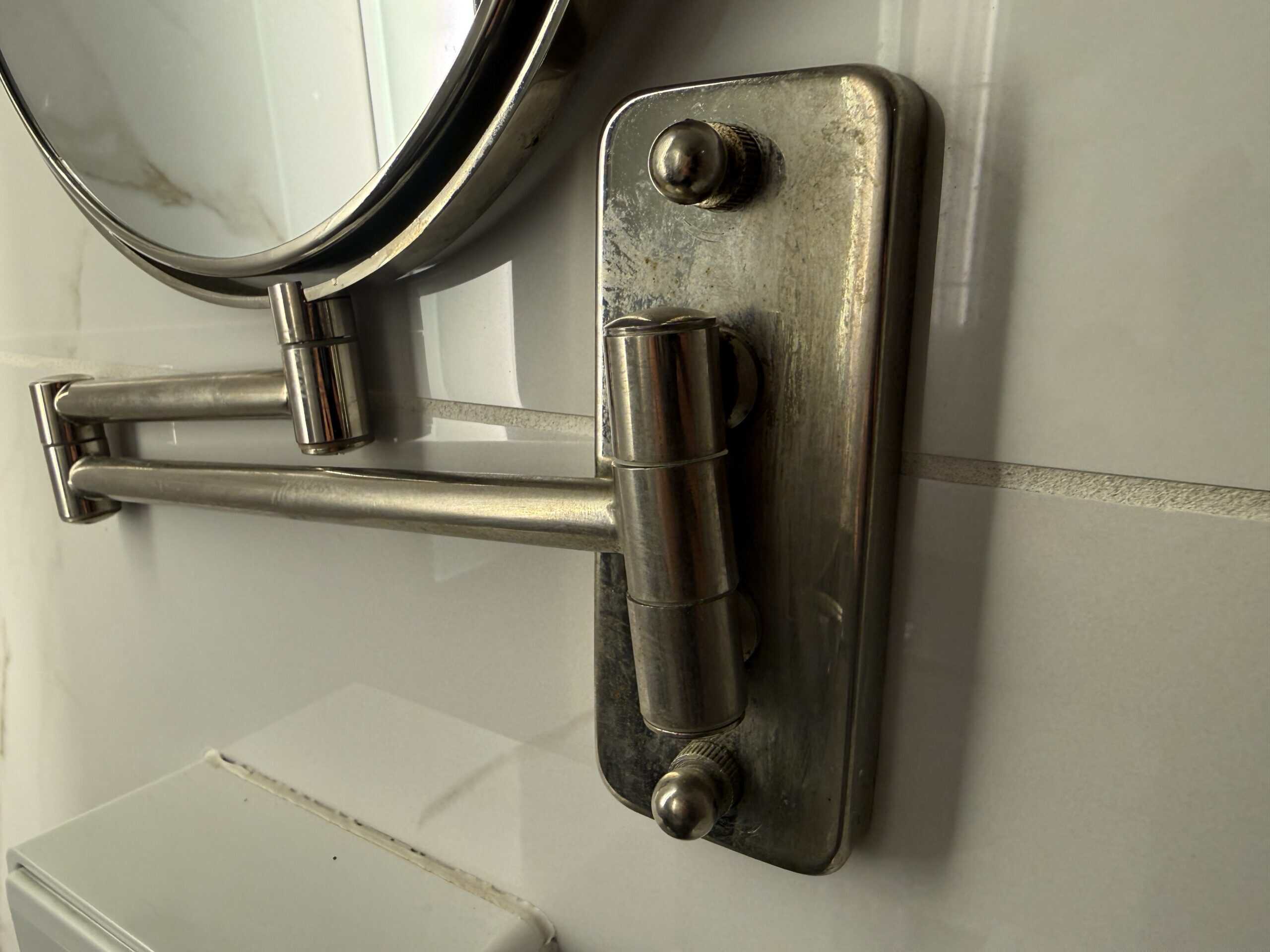 A wall mounted mirror that is scratched up.