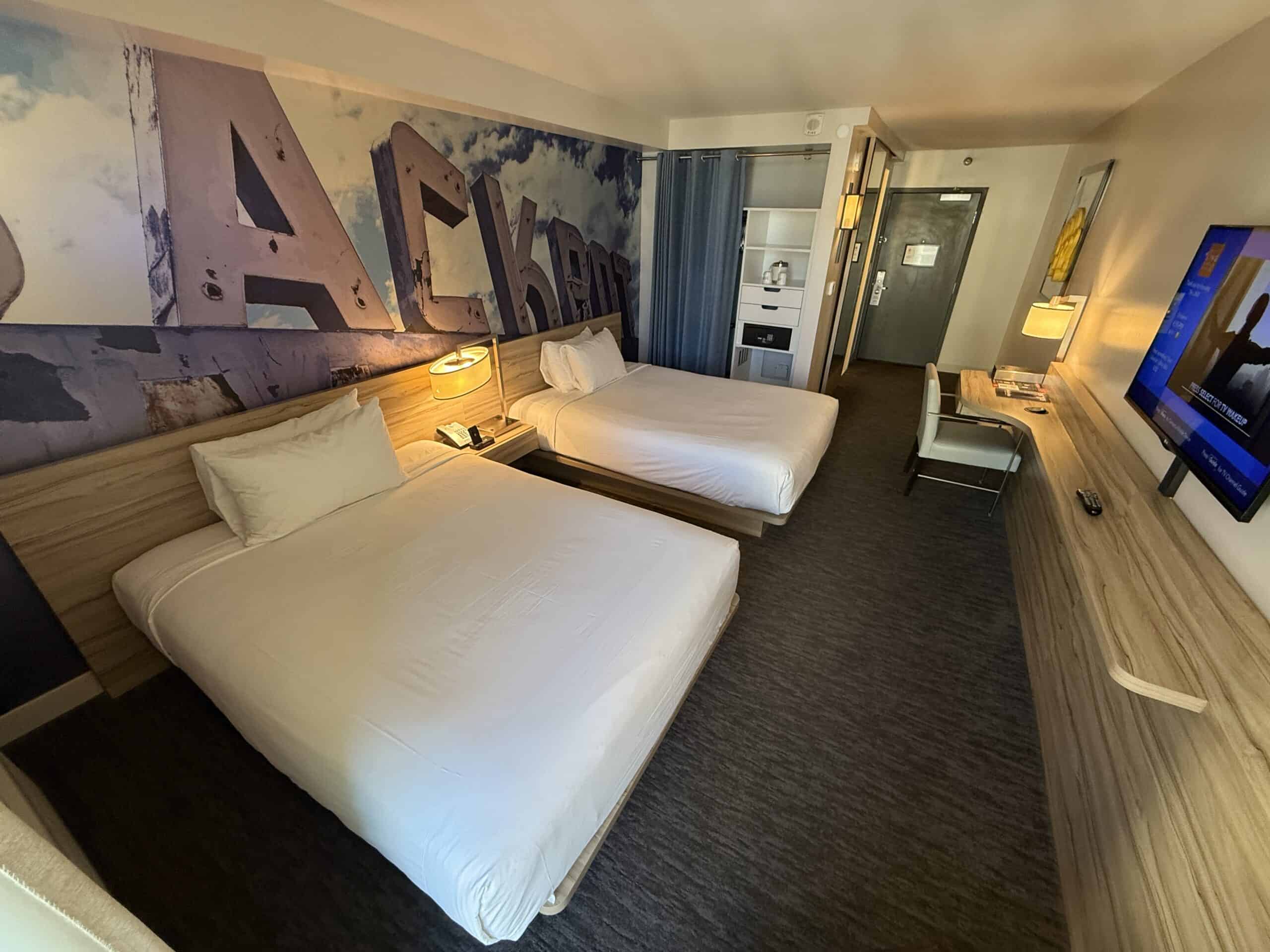Contemporary hotel room in Las Vegas with two beds and a large TV in the entryway in the background.