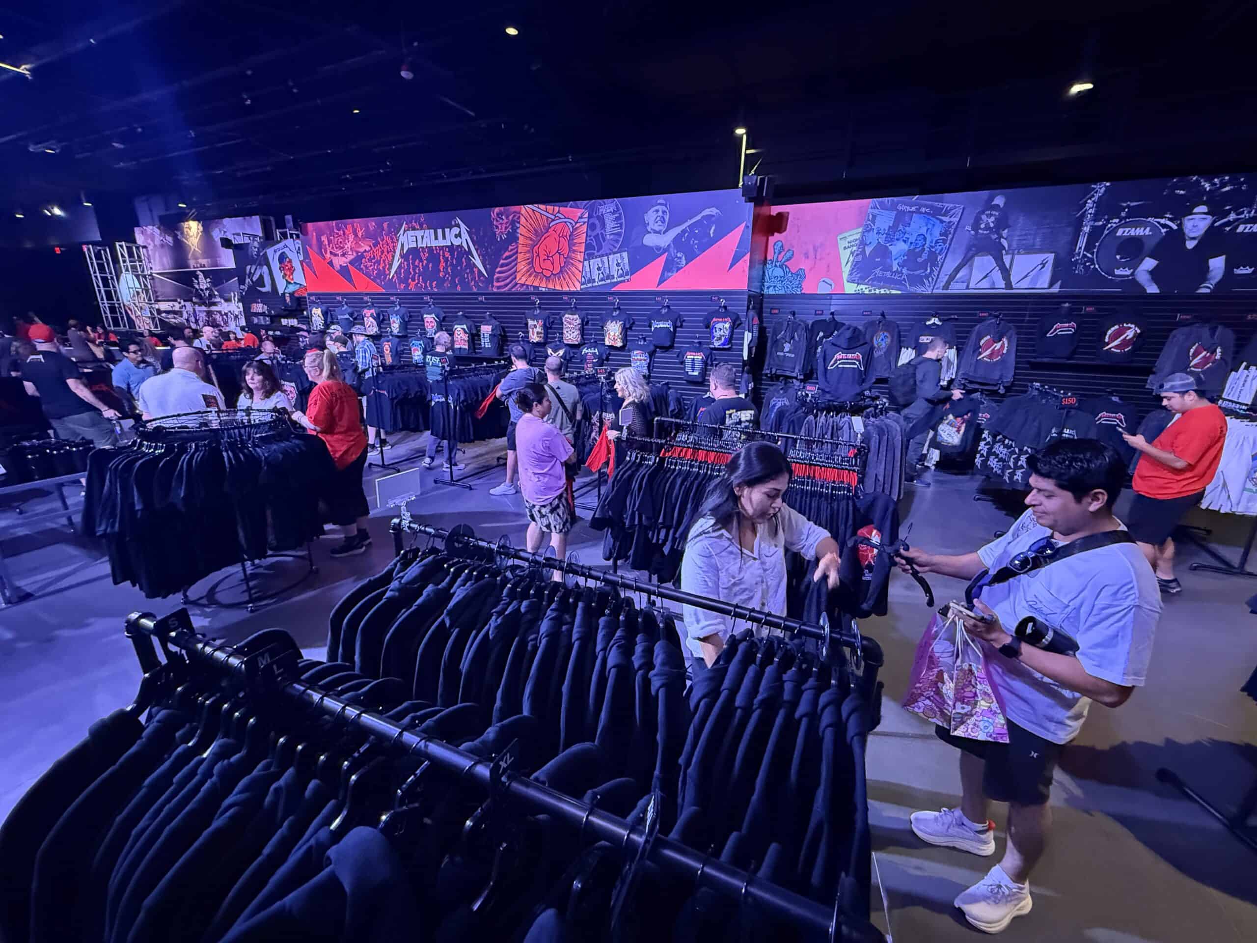 A wide angle shot of the merch area, which is packed with clothing racks.