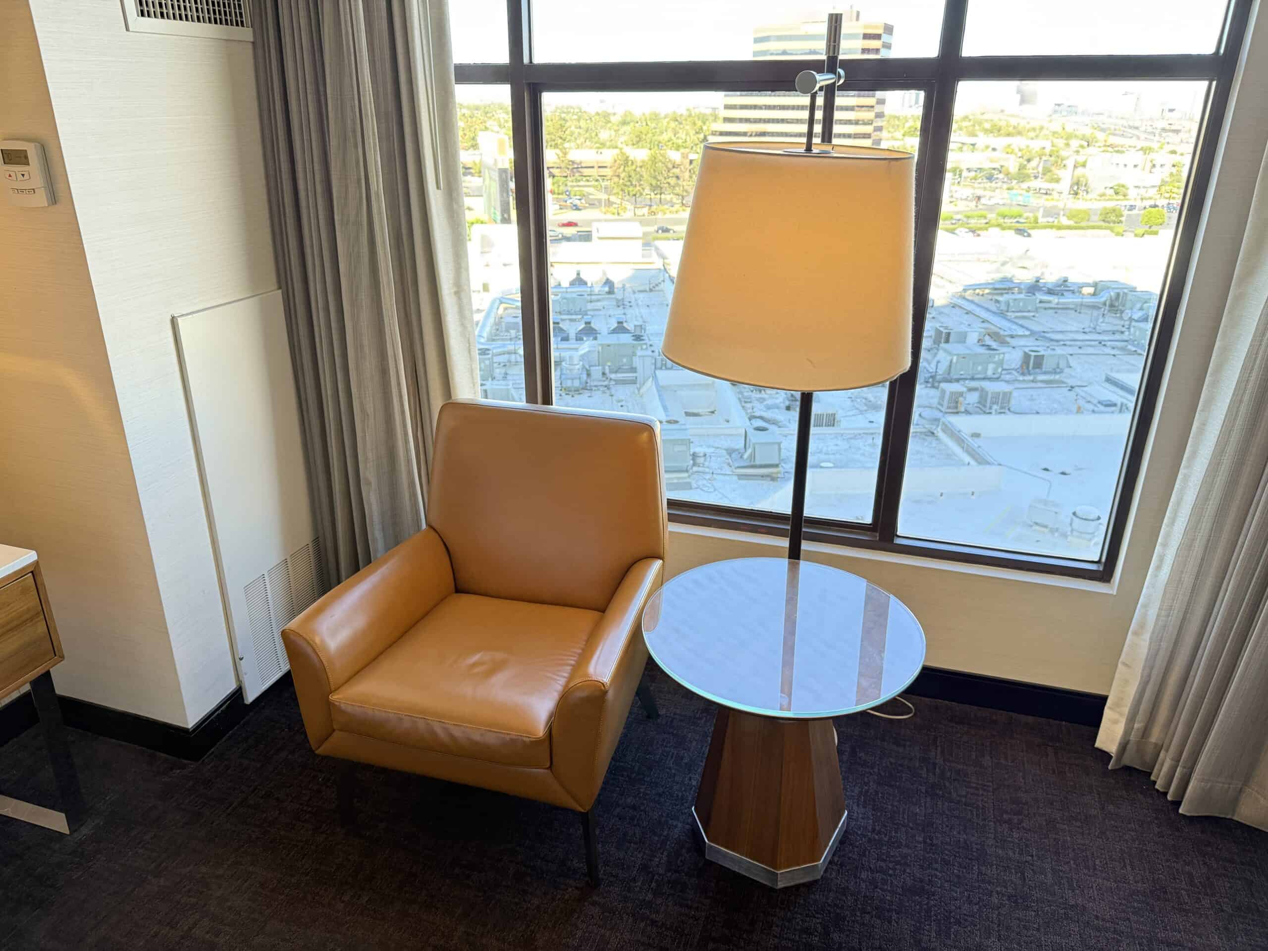A lamp and leather chair in front of the window.