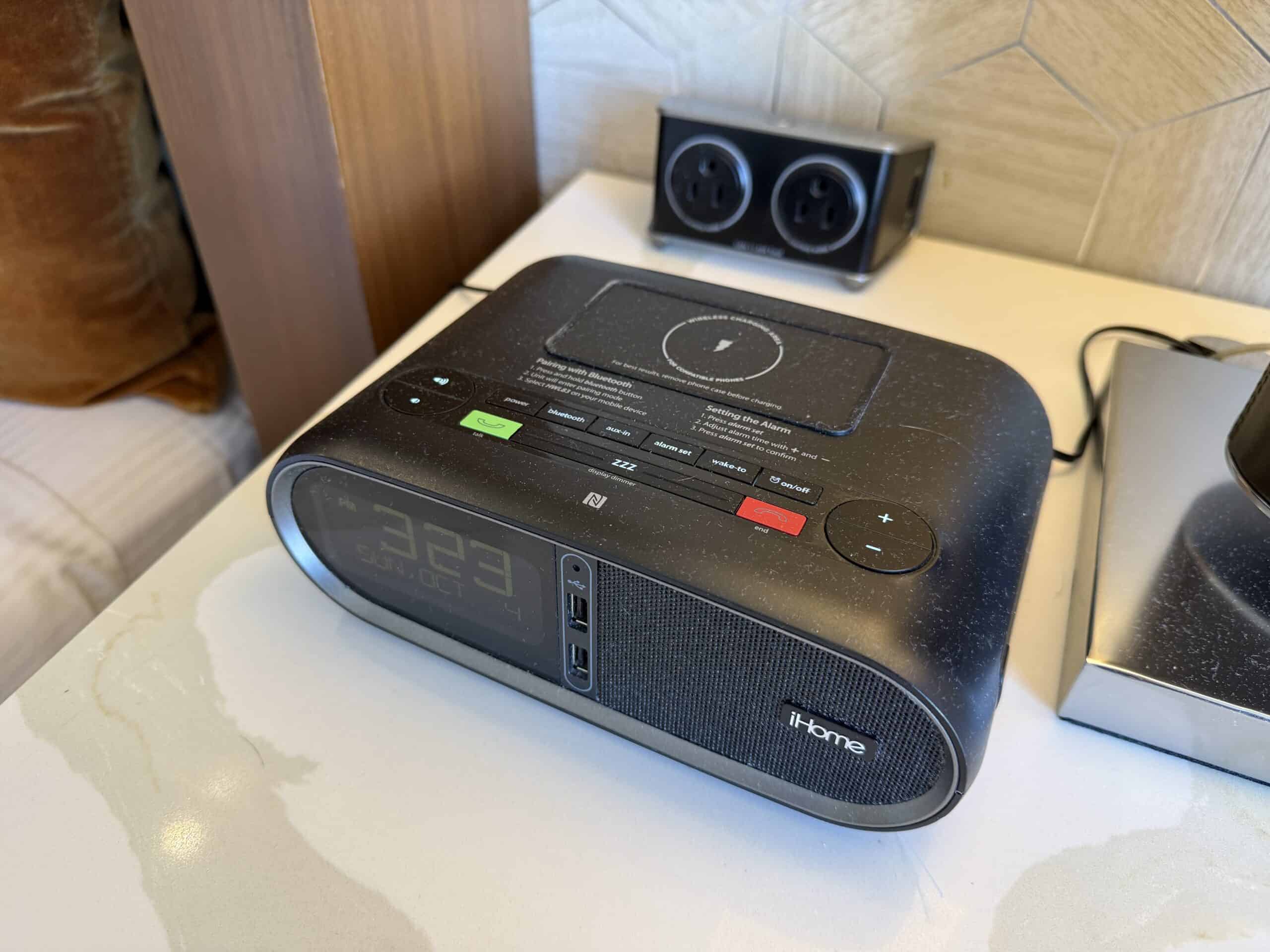A clock radio bedside, with wireless charging atop it.