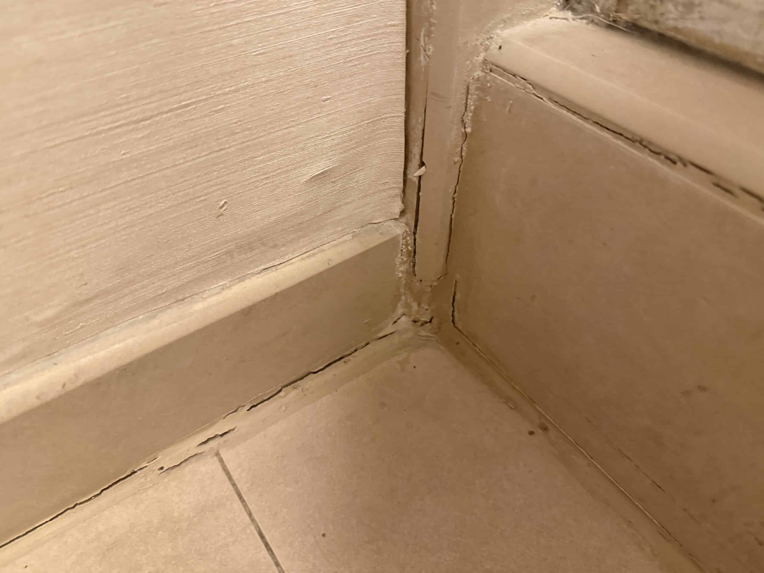 Another imperfect bathroom corner, with deteriorating caulk lines and peeling wallpaper.