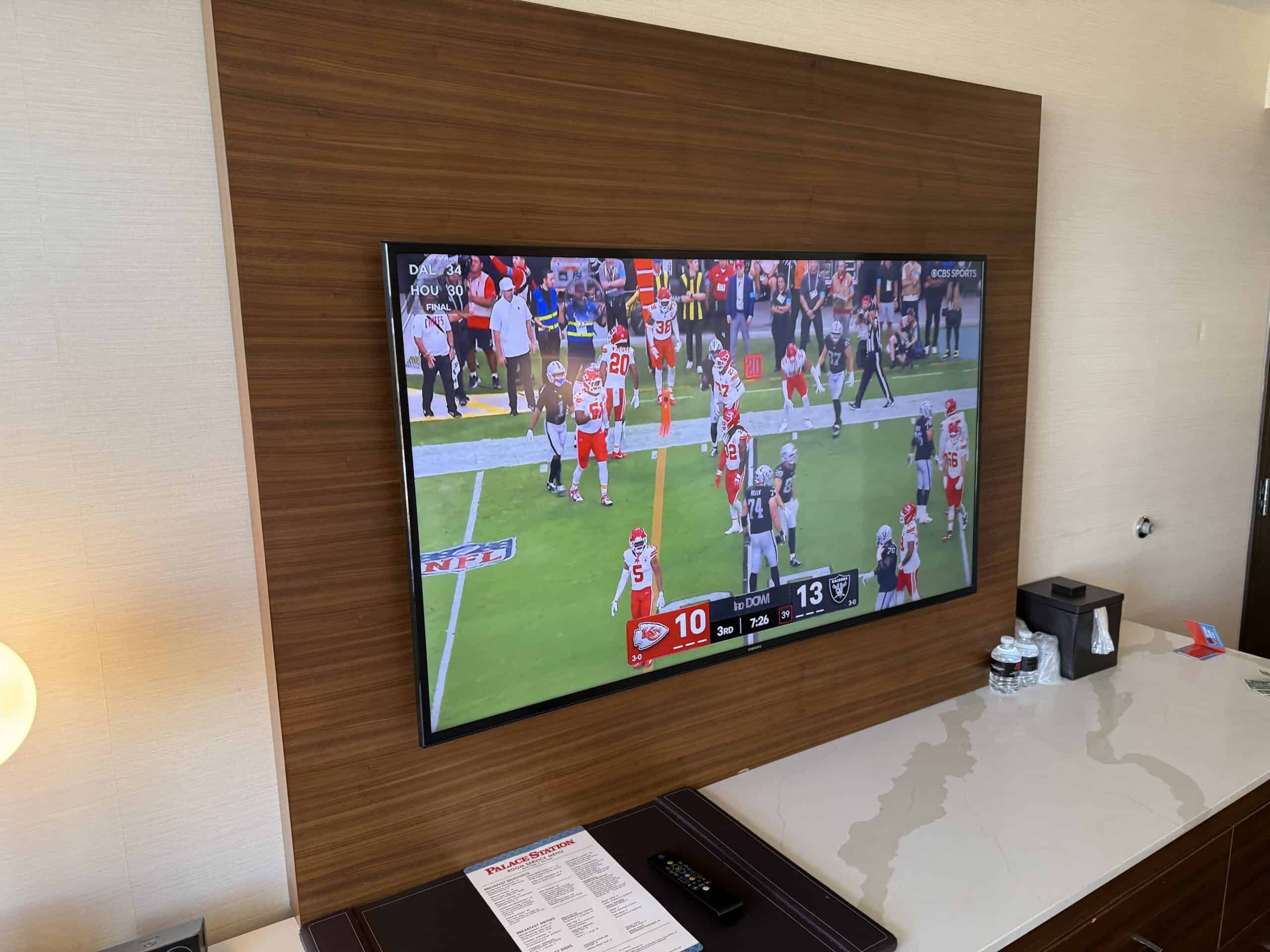 A 55" wall-mounted TV playing a football game.
