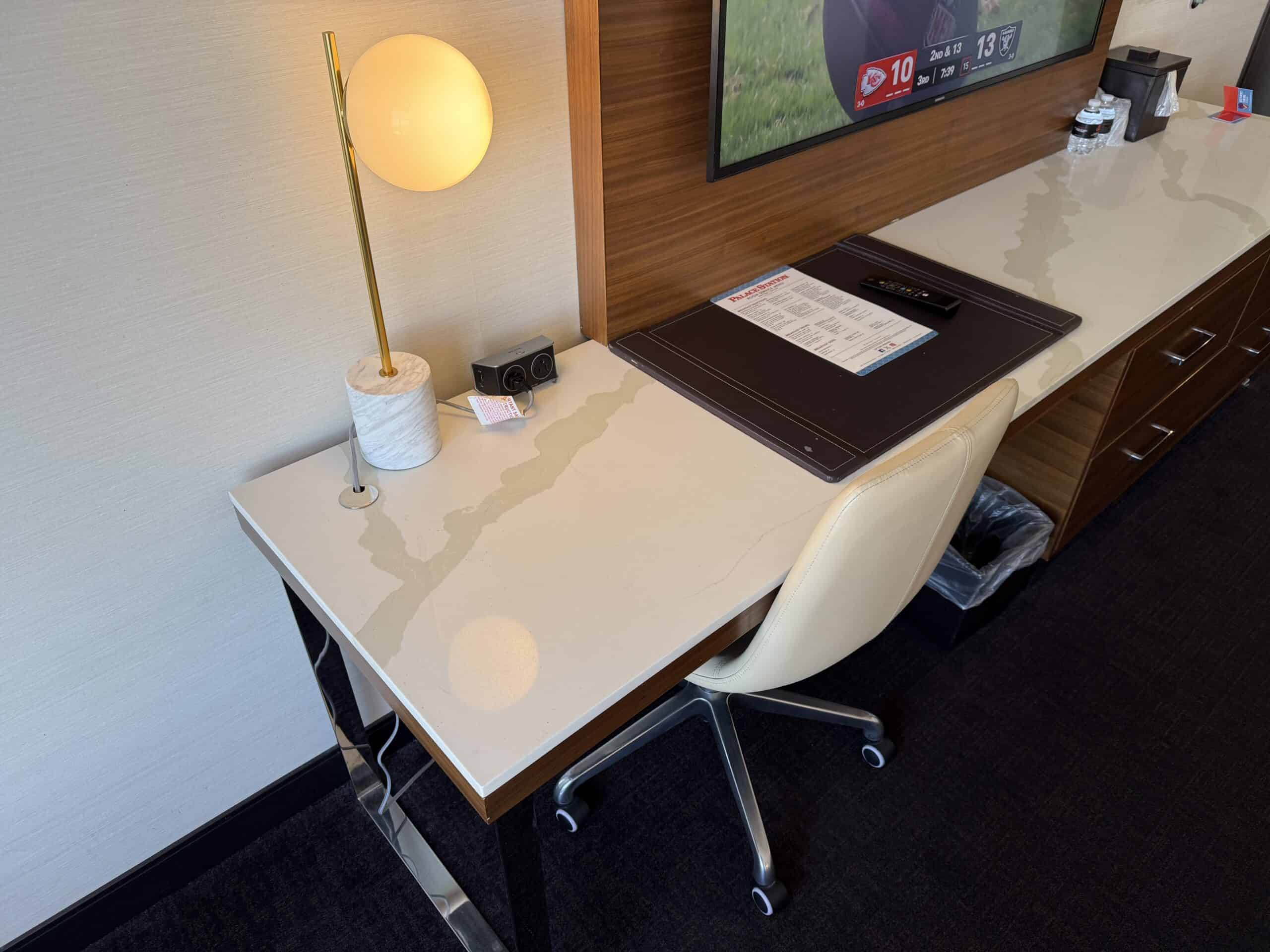 A small, stone topped work desk with a spherical decorative lamp sitting on it.