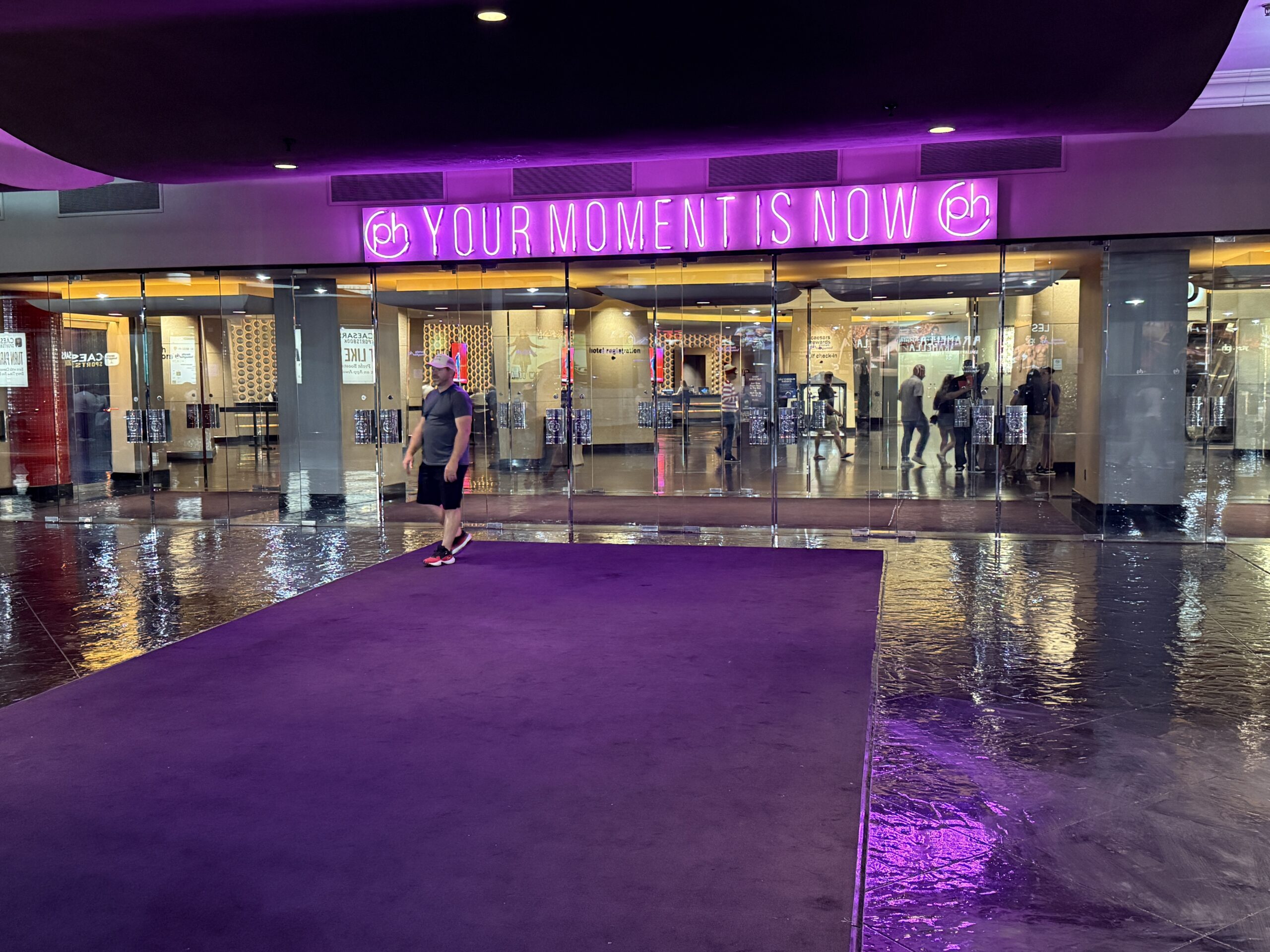 The entrance to Planet Hollywood with a neon sign above it that says "Your Moment Is Now".
