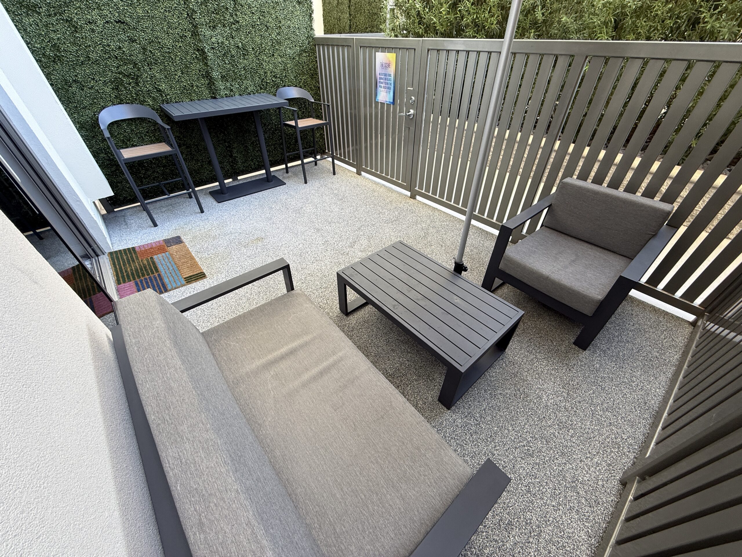 Another area of the patio, which shows the padded seats in the foreground and two high top seats and a table in the background.