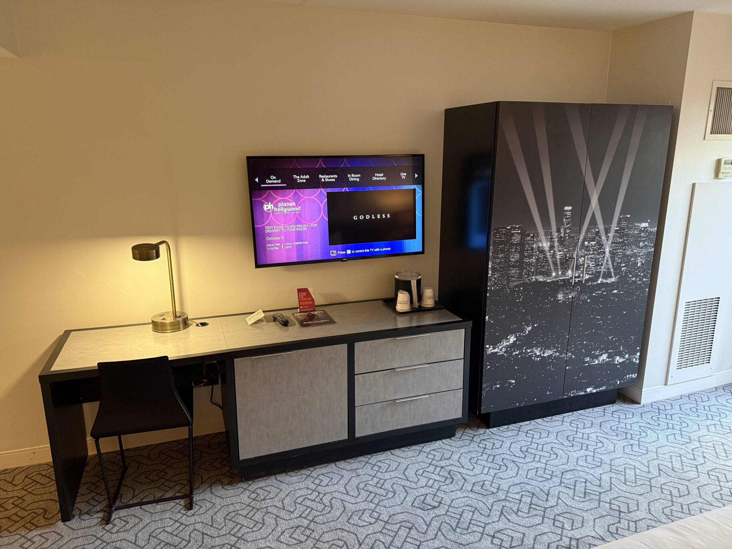 A wall nounted TV next to a armoire.