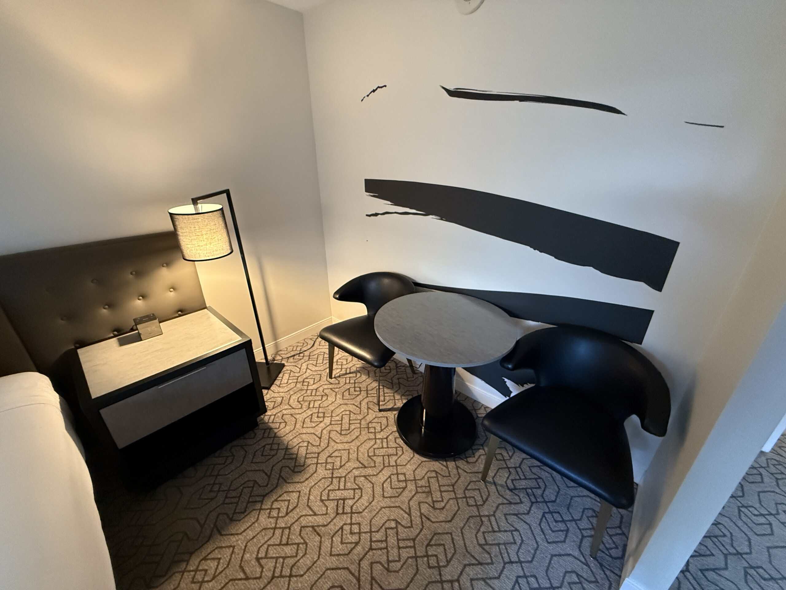 A circular table flanked by two chairs against a wall.