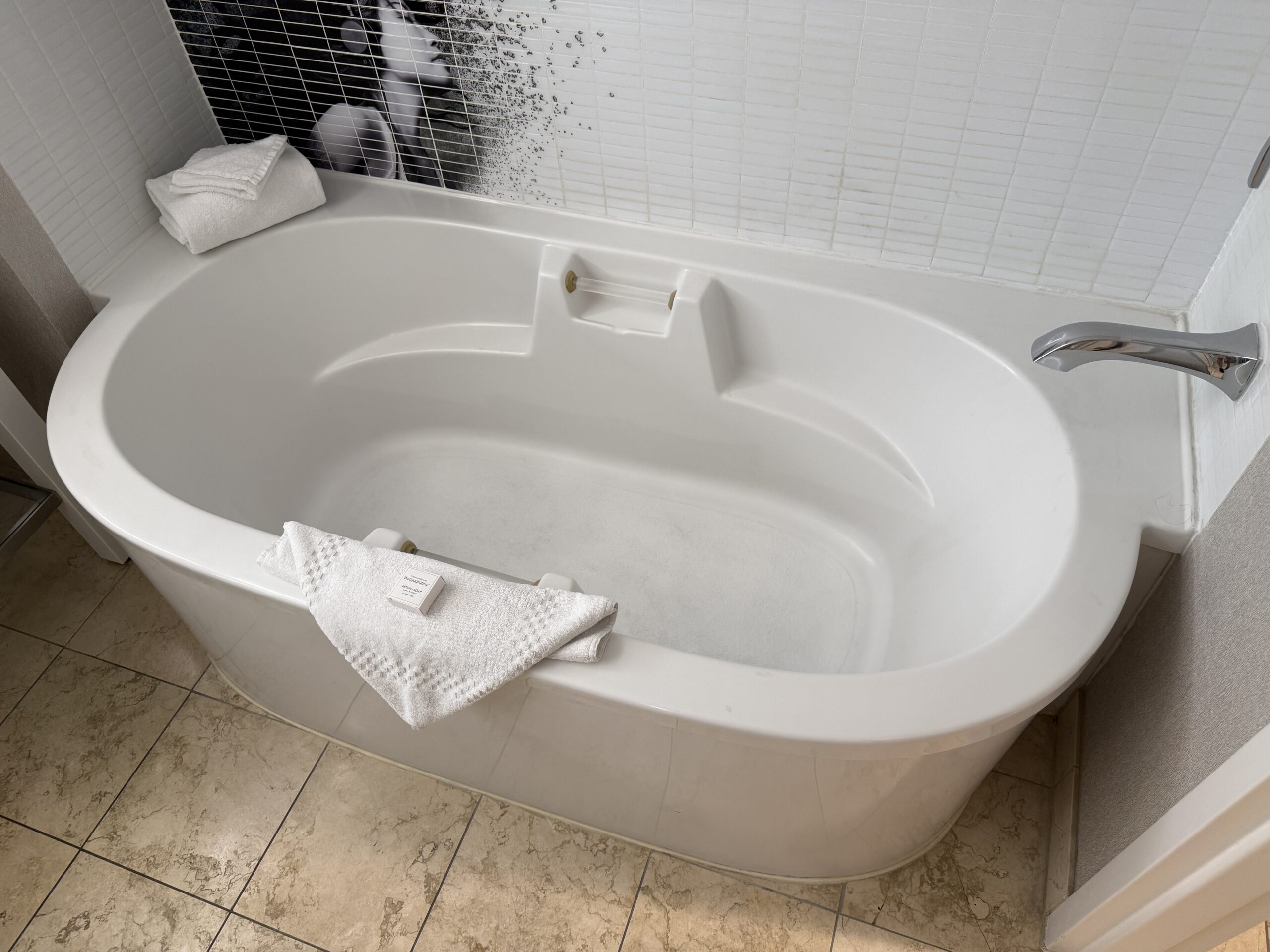 A close up of the bath tub, which is oval shaped and deep.