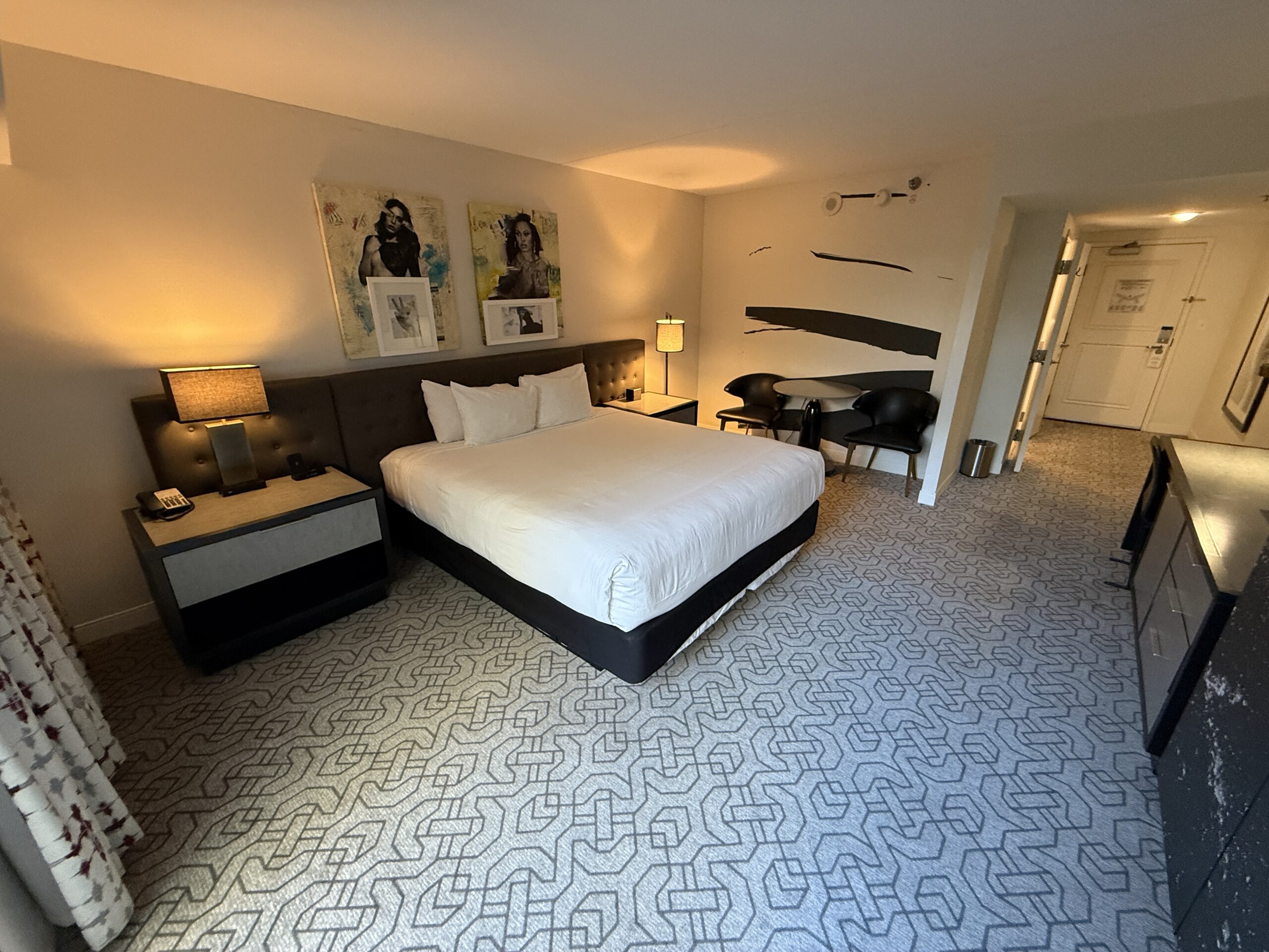 A wide angle view of the room that shows a king bed and the entryway in the background.