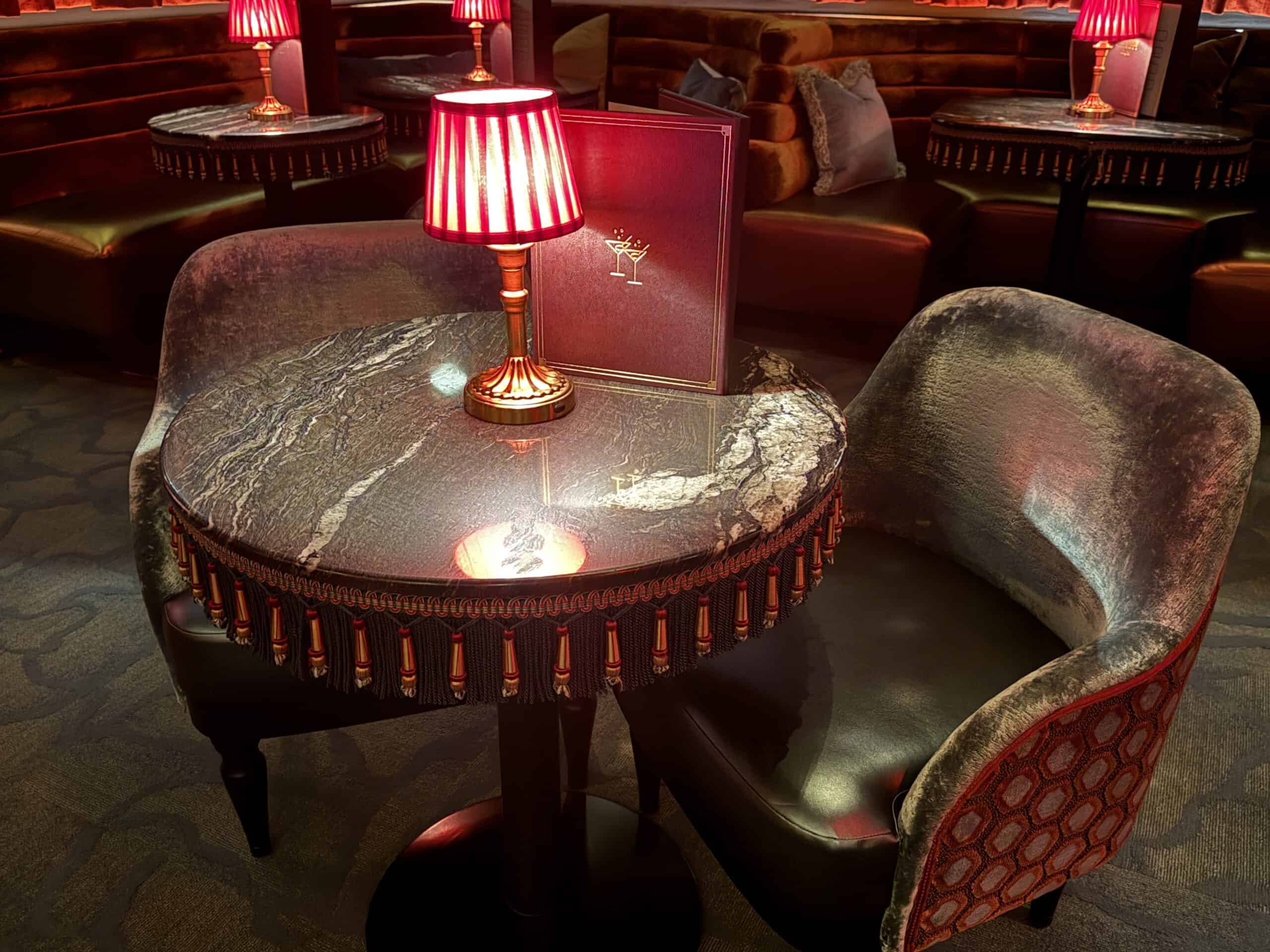 A close up of a table, which has a stone top and a red lamp atop it.